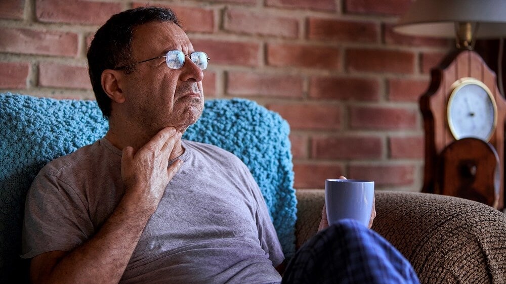 Man drinking tea to help with sore throat during flu season