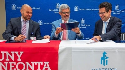 Dr. Tommy Ibrahim, Alberto Cardelle, & Darren Reisberg signing the partnership agreement