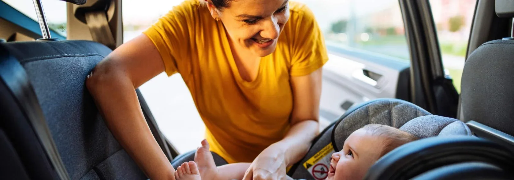 A woman securing her baby's carseat