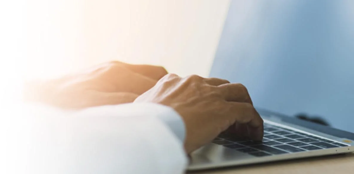 A pair of hands typing on a laptop
