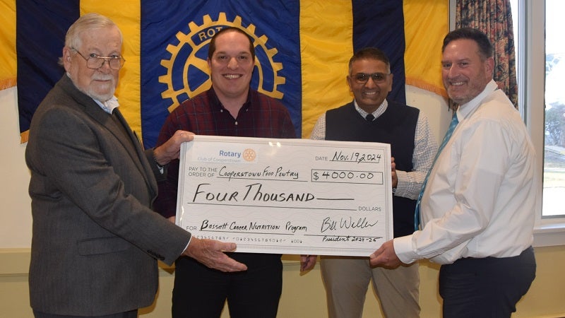 Rotary President Bill Waller presents the ceremonial $4K check to the Director of the Cooperstown Food Pantry, Will Kleffner, and the Chief of Hematology & Oncology at Bassett, Dr. Anush Patel, as well as the Program Coordinator of the Bassett Cancer Institute, Mark Kirby.