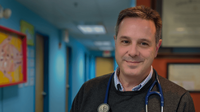  Dr. William Fredette smiles for the camera. He has a stethoscope around his neck. 