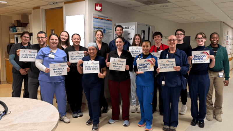 A group of nurses hold up signs celebrating the Beacon Award
