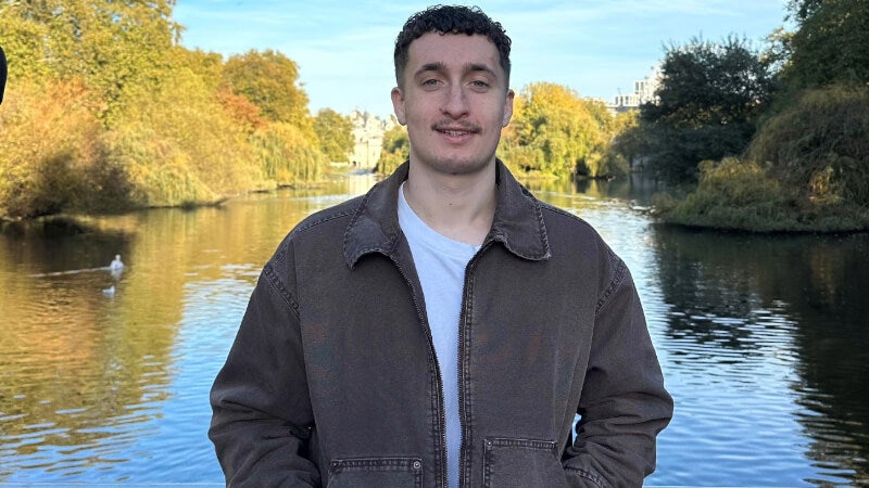 Dakota Basloe stands in front of a lake.