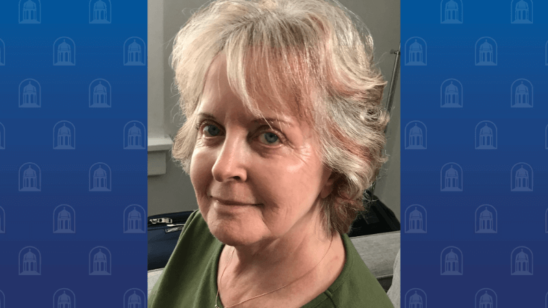 A woman is photographed. She has short, blonde hair and is looking at the camera.