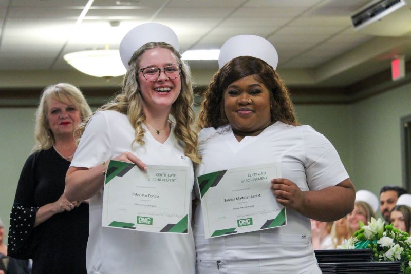 Rylee MacDonald (left) and Sabrina Martinez-Benoit accept clinical practice awards during the graduation program. 