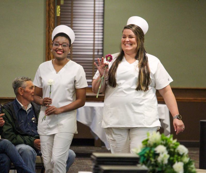 Jade Hull (left) and Breanna Austin enter the graduation ceremony during the processional, carrying carnations.
