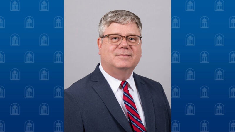 A man wearing a suit and tie is photographed.