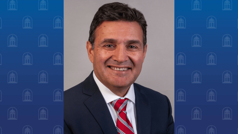 A man in a suit smiles for the camera. 