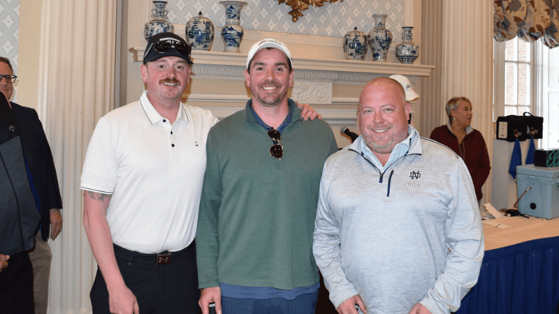 Three golfers stand together for a photo
