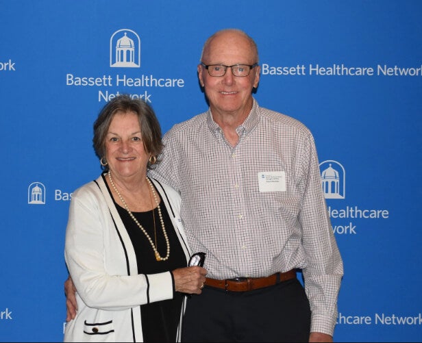  Two people stand side by side in front of a Bassett Healthcare Network backdrop.