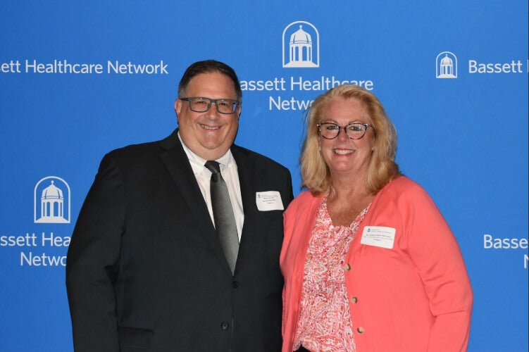  Two people stand side by side in front of a Bassett Healthcare Network backdrop.