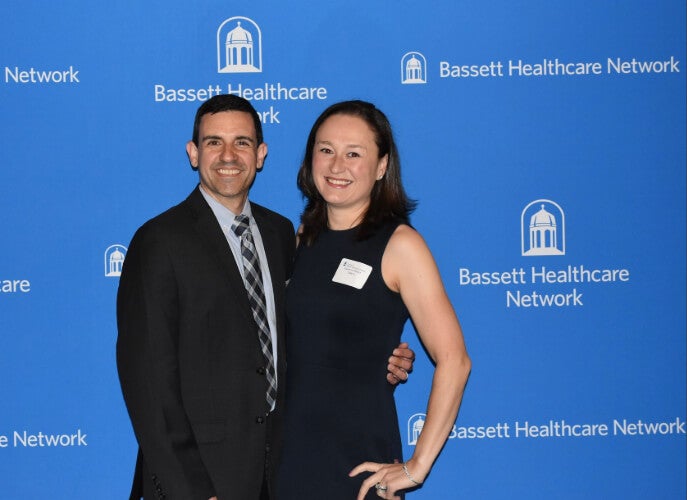 Two people stand side by side in front of a Bassett Healthcare Network backdrop.