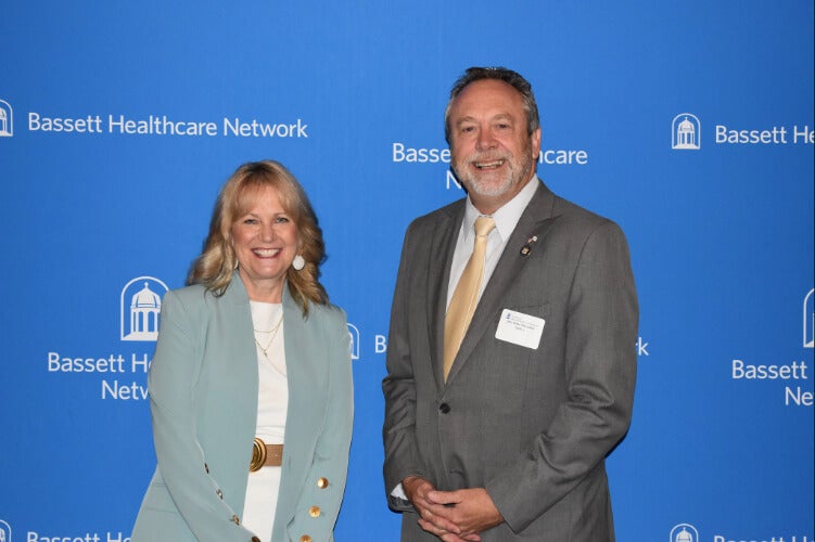  Two people stand side by side in front of a Bassett Healthcare Network backdrop.