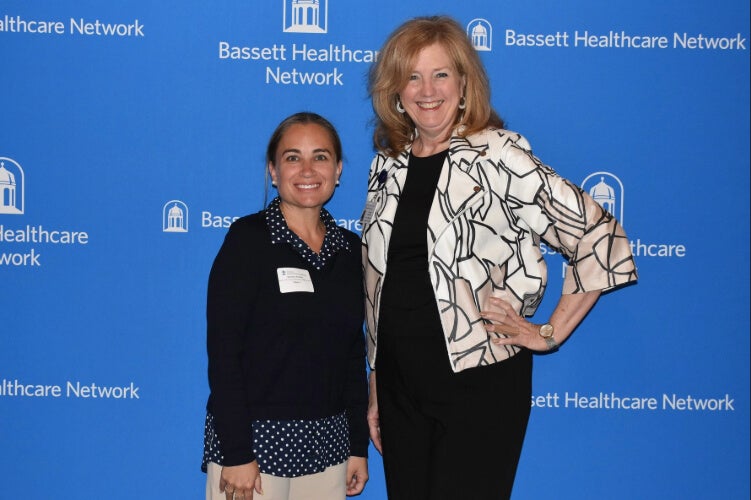 Two people stand side by side in front of a Bassett Healthcare Network backdrop.