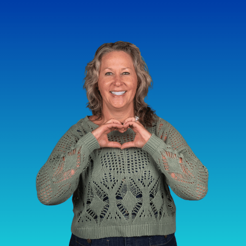  A woman in a green sweater making a heart shape with hands