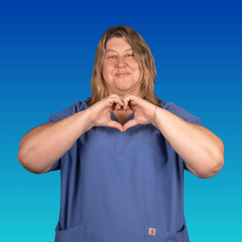 A woman in scrubs making a heart shape with her hands