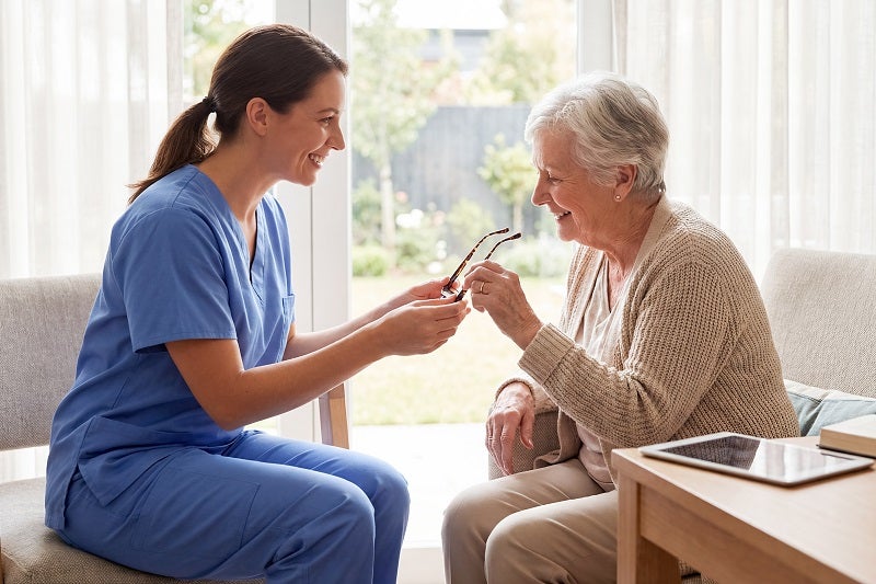 Nurse helping long-term care resident with glasses
