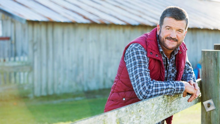 adult man outside leaning on fence