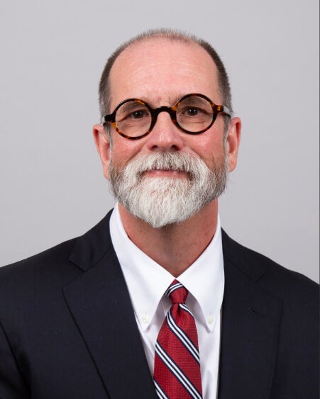 A man, Dr. Robert Leon, is photographed. He is wearing a suit, tie, and glasses.  