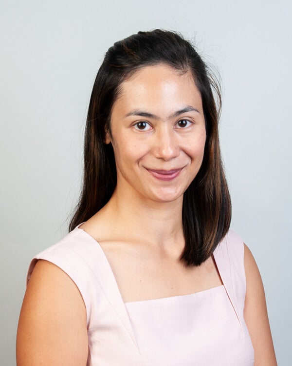 A woman, Dr. Abigail Quintos, is photogaphed. She has shoulder-length hair and is smiling.