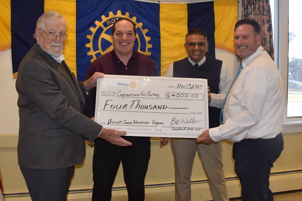 Rotary President Bill Waller presents the ceremonial $4K check to the Director of the Cooperstown Food Pantry, Will Kleffner, and the Chief of Hematology & Oncology at Bassett, Dr. Anush Patel, as well as the Program Coordinator of the Bassett Cancer Institute, Mark Kirby.