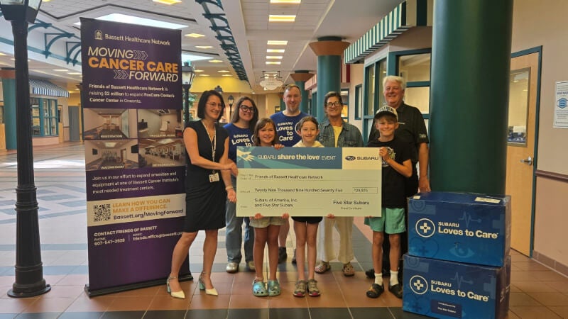 Eight people hold up a ceremonial check from Five Star Subaru's Share the Love event