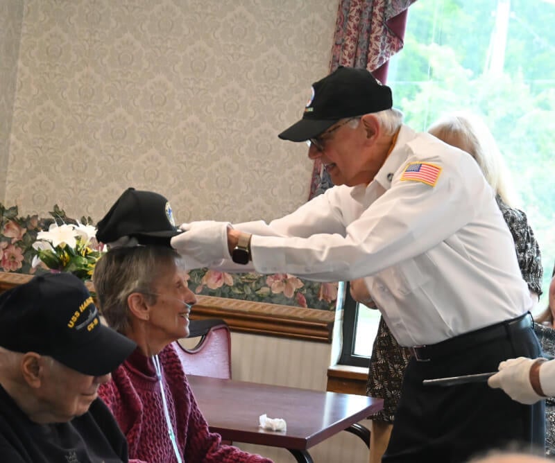 A VVA member places a hat on an elderly woman's head