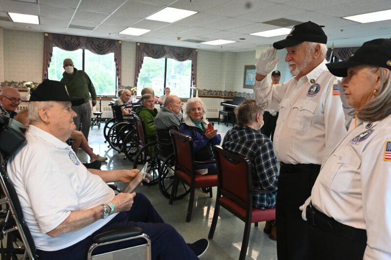 Two members of the VVA salute a man who has received his hat and certificate.
