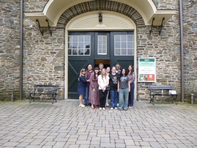 A group of 10 people is photographed outside a pair of doors.